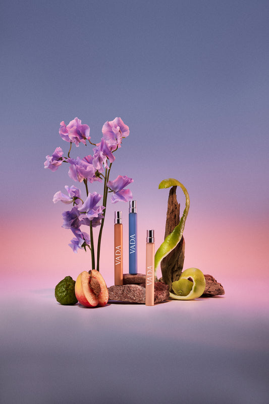 Vada perfume bottles with flowers and fruits on a gradient background