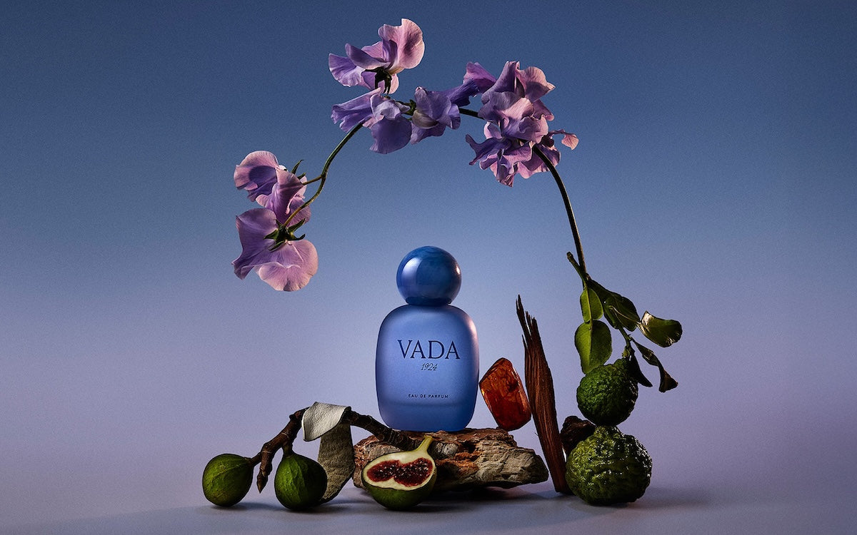 Blue Vada perfume bottle with flowers and fruits on a gradient background