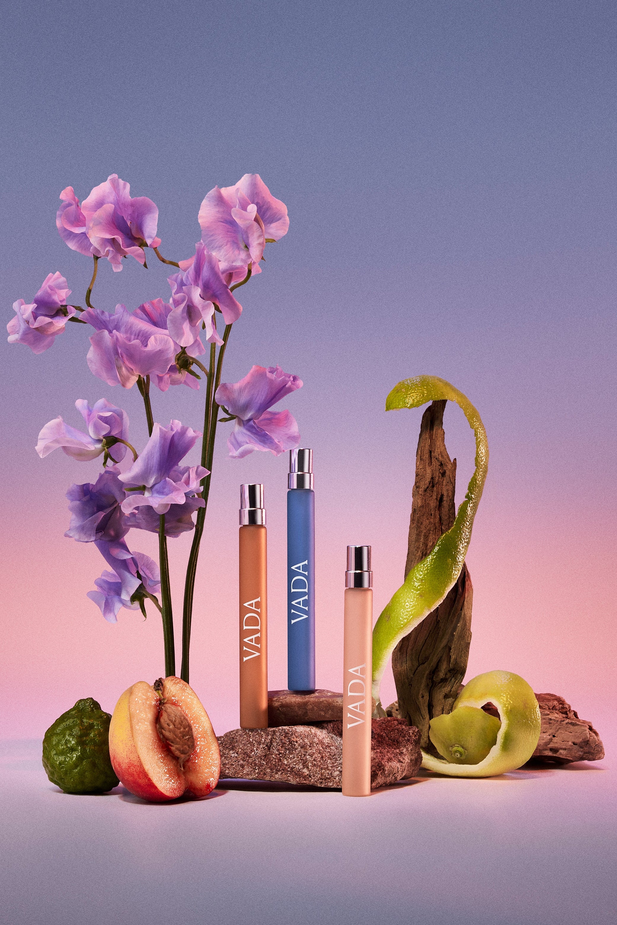 Vada perfume bottles with flowers and fruits on a gradient background
